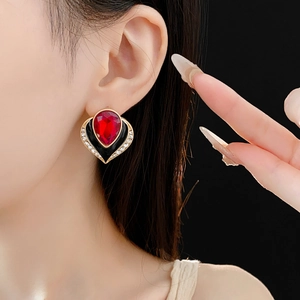 Close-up of vintage heart earring with red teardrop crystal and black enamel
