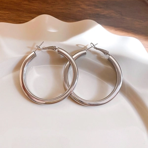 Detailed view of silver hoop earrings on a ceramic dish with polished mirror finish