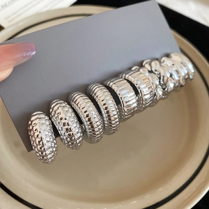 Detail of silver drop and C-shaped earrings with textured ribbing on a display card