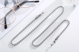 Silver steel beaded eyewear chain with white silicone anti-slip loops on a magazine