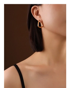 Close-up of model wearing polished gold U-shaped geometric earrings in 18K gold finish