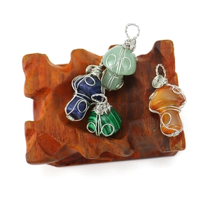 Handmade woven crystal mushroom pendants in lapis lazuli and agate on a wooden stand