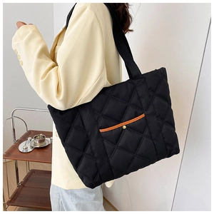 Detail of black quilted nylon tote bag with small front pocket and metal snap button
