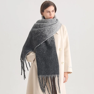 Detail of gray gradient knit scarf with tassels shown on a model for winter styling
