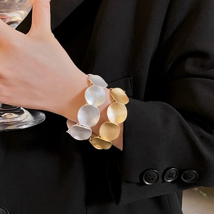 Macro shot of minimalist silver and gold circular concave metal bracelets on a model