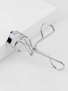Silver stainless steel eyelash curler featuring a spring mechanism and black silicone pad