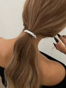 Close-up of textured silver metal ponytail cuff hair ring accessory on model's hair