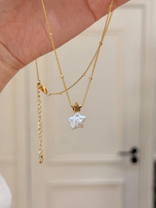 Gros plan d'un pendentif perle baroque en forme d'étoile sur une chaîne dorée