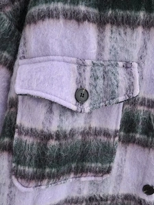 Detail of purple plaid wool coat fabric with brushed texture and flap pocket button