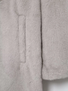 Close-up of the plush grey faux fur material and side pocket detail on a long winter coat