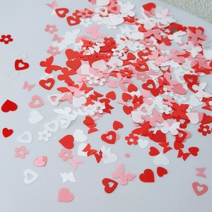 Flat lay of pink and white heart, flower, and butterfly nail sequins for Valentine's Day