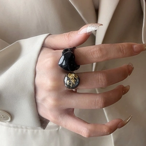 French style resin heart and gold foil ring set worn on model hand against beige blazer