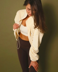 Detail of off-white fleece zip-up hoodie paired with brown leggings on model
