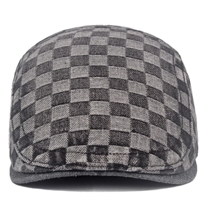 Detail of grey and black checkered ivy cap with vintage denim texture on white background