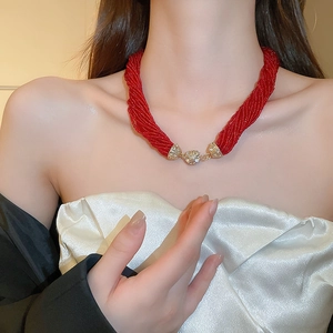 Detail of red multilayer beaded necklace with gold zircon accents on a female model