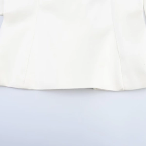 Détail de l'ourlet du chemisier en satin blanc montrant les finitions et la couture précise