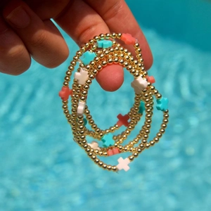 Set di bracciali a sfere dorate con ciondoli a croce colorati a bordo piscina