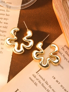 Detail shot of irregular gold wave earrings on vintage book pages background