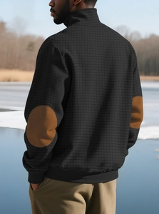 Detail der schwarzen Steppjacke für Herren mit braunen Ellbogen-Patches und Waffelstruktur