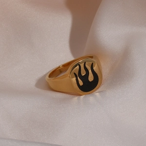 Close-up of gold stainless steel signet ring with black enamel flame on silk background