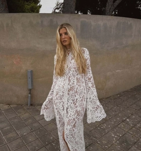 Dettaglio dell'abito in pizzo bianco con motivi floreali, scollo a V e maniche a campana