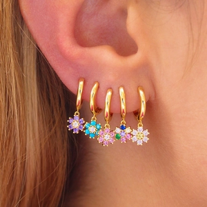 Close-up of five colorful crystal flower hoop earrings worn on ear for elegant style