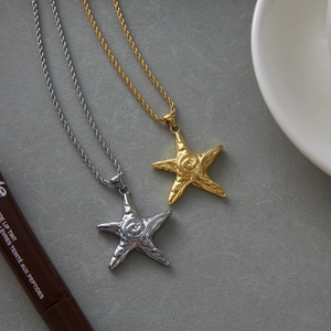 Detailed shot of starfish necklaces in gold and silver with rope chain on stone