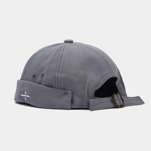 Detail of dark grey Miki hat with white division sign embroidery and metal adjustment strap