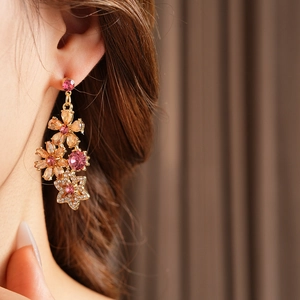 Close-up of vintage gold floral drop earrings with pink and champagne rhinestones on model