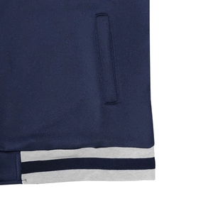 Detailed view of dark blue jacket pocket and striped ribbed hem on knit baseball cardigan