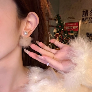 Close-up of winter style pearl earrings with light camel faux fur pom-poms on model