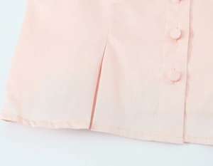 Close-up of pink blouse hem with round buttons and precise stitching details