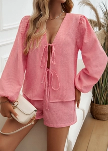 Dettaglio del set due pezzi a quadretti rosa con top a portafoglio e maniche a lanterna