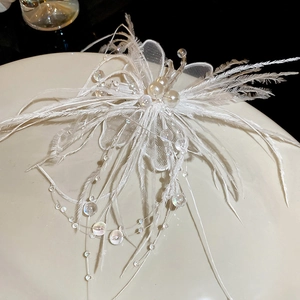 Détail de pince à cheveux en plumes blanches avec perles, pétales de dentelle et glands