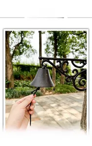Detail of vintage cast iron doorbell with scrolling bracket being pulled in a garden