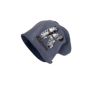 Grey-blue slouchy knit beanie featuring a large letter K patch and silver rivet details