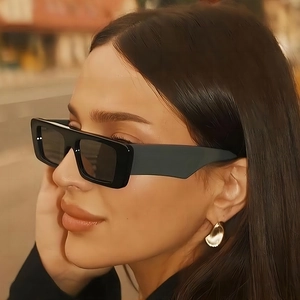 Chic black rectangular wide-leg sunglasses worn by a model in an urban outdoor setting