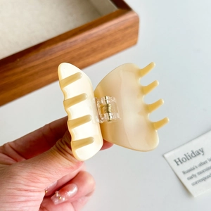 Beige butterfly acetate hair claw clip for elegant hairstyles held in hand with clear detail