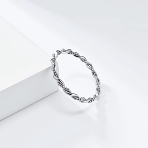 Detailed view of silver twist cable ring on white geometric stand in soft light