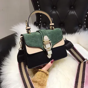 Close-up of matte dark green flap with gold twist-lock and striped woven shoulder strap