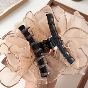 Détail d'une pince à cheveux élégante en organza beige avec des nœuds multicouches doux
