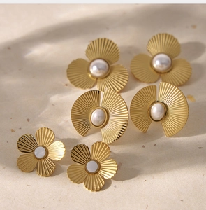 Détail de boucles d'oreilles dorées mates avec texture plissée et perles élégantes