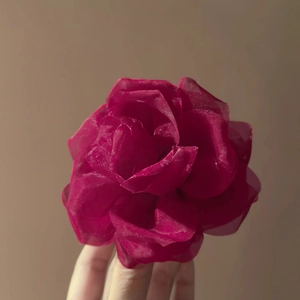 Dettaglio ravvicinato di una pinza per capelli con rosa in tessuto rosso scuro e organza