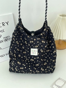 Close-up of black floral quilted tote bag with checkered strap and metal snap closure