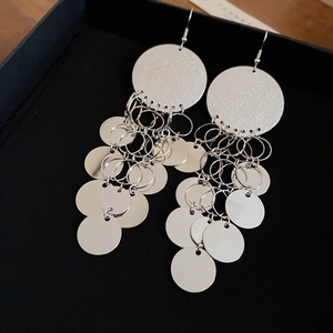 Detail of silver layered disc tassel earrings showing reflective metallic texture