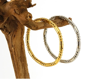 Detail of beaded bamboo style 18K gold and silver stainless steel bangles on wood