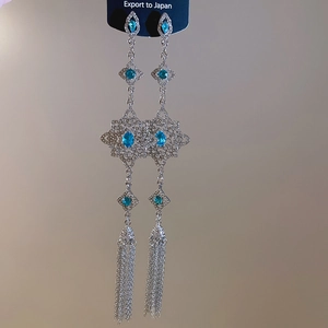 Macro view of vintage silver earrings with light blue gemstones and long chain tassels
