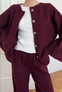 Detail view of burgundy knitted cardigan with buttons and matching pants texture