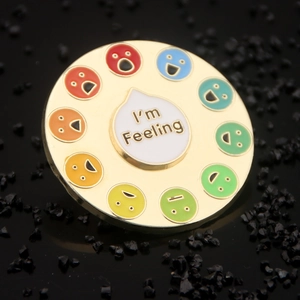 Macro shot of colorful enamel rainbow spinner pin with different social battery emojis