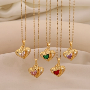 Goldene Herz-Halsketten mit bunten Kristallen auf elegantem weichem Stoffhintergrund